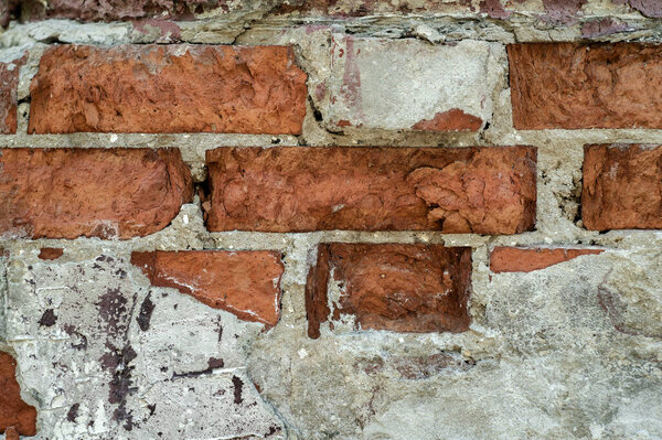 Texture of the old cracked brick wall of the building with remnants of cement