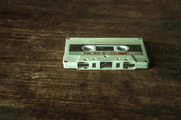 Old white audio cassette on a wooden table
