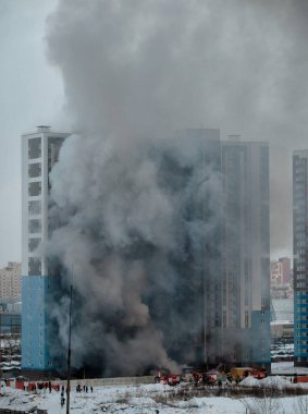 Yüksek katlı bir binada yangın. Bir sürü duman ve itfaiye aracı.
