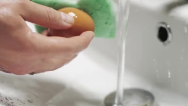 Close-up of hands wash the egg with soap under running water. — Stock Video