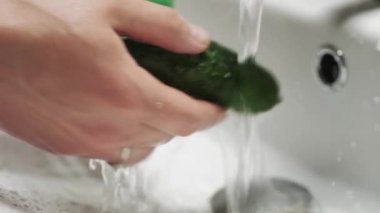 Salatalığı akan suyun altında elle yıka. Sağlıklı beslenme.