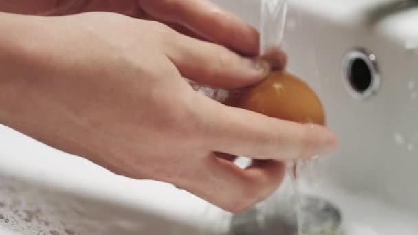 Closeup of hands washing a chicken egg under water jets. — Stock Video