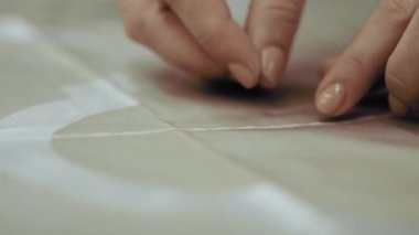 Terziyi ayarlar, kumaşı iğnelerle keser..