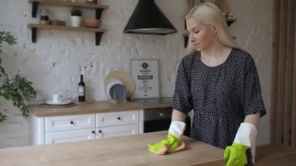 Νεαρή νοικοκυρά φορούν λαστιχένια προστατευτικά γάντια καθαρίζει ξύλινη επιφάνεια και χαμόγελο 4K — Αρχείο Βίντεο