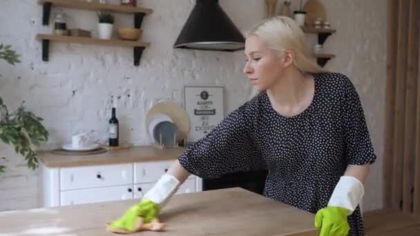 Νεαρή νοικοκυρά φορούν λαστιχένια προστατευτικά γάντια καθαρίζει ξύλινη επιφάνεια και χαμόγελο 4K — Αρχείο Βίντεο