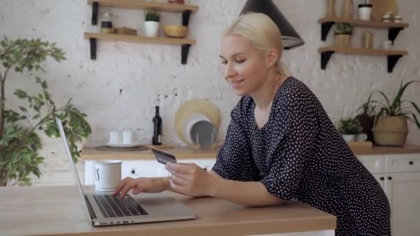 Femme debout dans la cuisine entre les données d'une carte en plastique dans l'ordinateur — Video