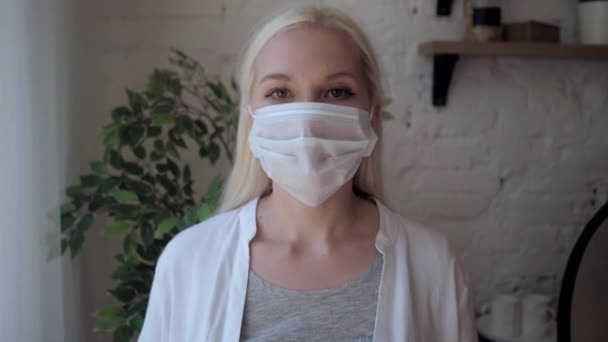 En vacker ung kvinna tar en medicinsk mask och ler. — Stockvideo