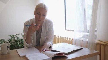 Masada ders çalışan kız öğrenci. Defterdeki bir kitaptan notlar alıyor.