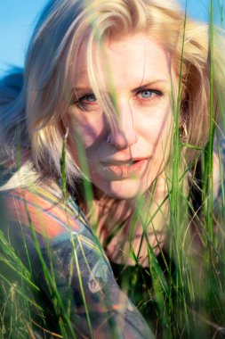 Çimenlerde dövmeleri olan güzel sarışın kadın.