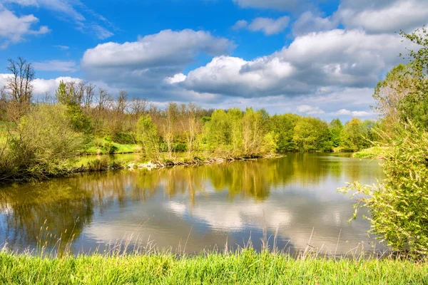 Paisaje primaveral con estanque, árboles y cielo nublado —  Fotos de Stock