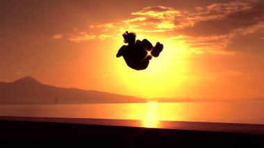 Siyah adam günbatımı arka plan üzerinde atlama silüeti