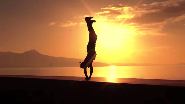 Black silhouette of man jumping on sunset background