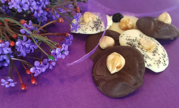 Glazed cookies with hazelnuts and poppy seeds serving with violet flowers