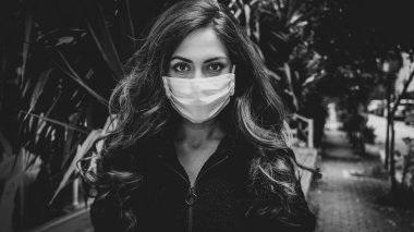 Sokaktaki Coronavirus 'u korumak için tıbbi maske takan genç bir kadın.