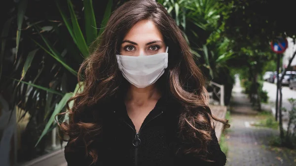 Sokaktaki Coronavirus 'u korumak için tıbbi maske takan genç bir kadın.