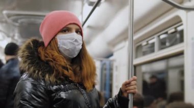 Tıbbi maske takan kadın metroya biniyor, koronavirüsten korunuyor.