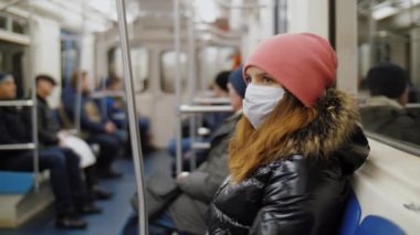 Tıbbi maske takan kadın metroya biniyor, koronavirüsten korunuyor.
