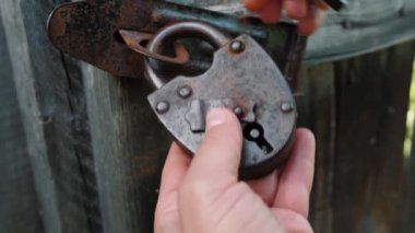 Eski, paslı demir kilit, eski ahşap kapının üzerinde. El kilidi anahtarla kapatır