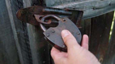 Eski, paslı demir kilit, eski ahşap kapının üzerinde. Kilidi anahtarla aç