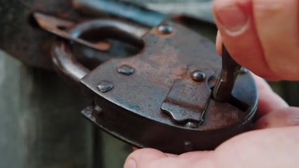 Fechadura de ferro enferrujado vintage velho na porta de madeira retro. Cadeado aberto à mão com chave — Vídeo de Stock