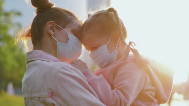 仮面の母は腕の抱擁で悲しい娘を保持し、彼女をなだめる,コロナウイルスの流行 — ストック動画