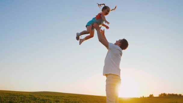 Padre gettare bambino felice in aria al tramonto, papà giocare con figlia adorabile — Video Stock