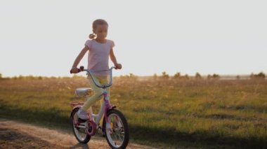 Gün batımında bisiklet süren mutlu çocuk, dışarıda eğleniyor.