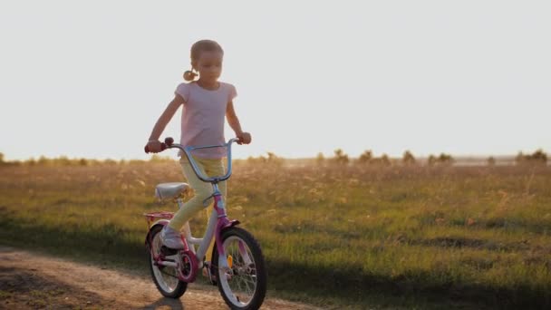 Niño feliz montar en bicicleta en el campo al atardecer, divertirse al aire libre — Vídeos de Stock