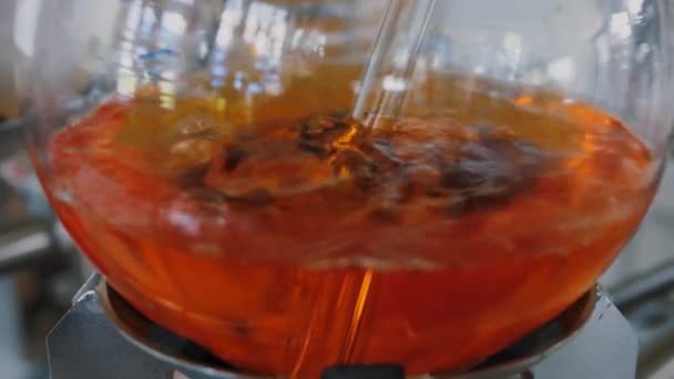 Κεχριμπαρένιο πορτοκαλί υγρό βράζει και φυσαλίδες σε μια γυάλινη φιάλη, χημικό εργαστήριο — Αρχείο Βίντεο