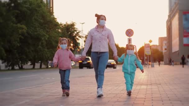 Мать с дочерьми носит медицинские защитные маски для лица, ходит по улице — стоковое видео