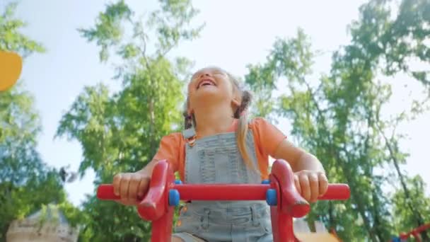 Gadis kecil yang cantik mengendarai kuda untuk menyeimbangkan ayunan, gadis kecil tertawa dan bersenang-senang — Stok Video