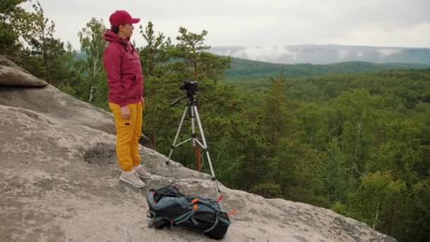 Vrouw toerist staat op piek, het nemen van foto 's van de natuur landschap met behulp van statief — Stockvideo