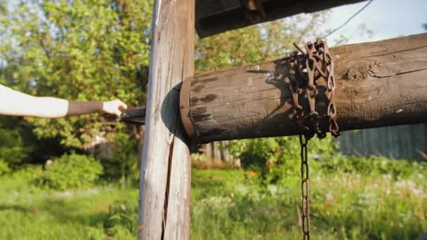 Mano gira maniglia della catena di legno tronco secchio sollevamento con acqua dal pozzo manuale — Video Stock