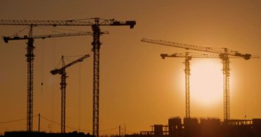 Gün batımında inşaat alanı, zaman ayarlı. Vinçler inşaat alanında çalışıyor