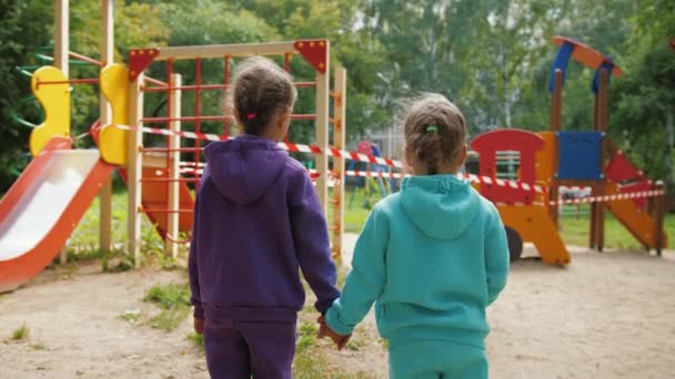 Dos niñas de pie cerca de un patio cerrado durante la pandemia de coronavirus — Vídeos de Stock