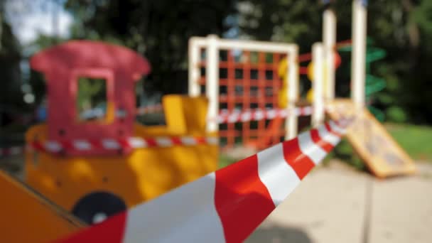 Red caution tape due coronavirus pandemic, childrens playground is closed — Stock Video