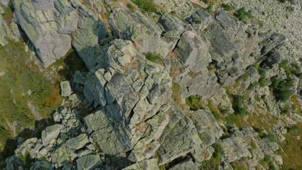 Drone volando sobre el pico de la montaña con rocas desnudas rodeadas de vegetación — Vídeo de stock