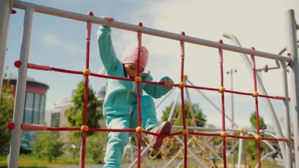 Nettes kleines Mädchen klettert Seilwand und spielt auf Spielplatz — Stockvideo