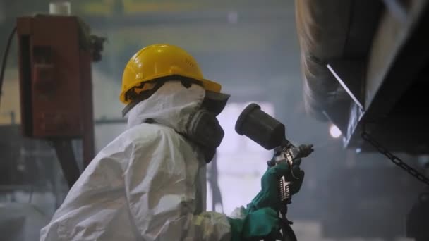 Fabriksarbetare i skyddsdräkt målar ytan på tågvagnen med sprutpistol — Stockvideo