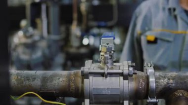 Yakın plan: modern rafineri fabrikası olan boru hattında işçi el vanası kapanıyor