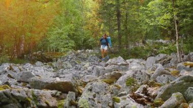 Sırt çantalı bir kadın kayalara tırmanıyor, taşlara tırmanıyor, zor bir yürüyüş.