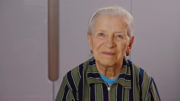 Egy boldog idős nő portréja, aki mosolyog, a kamerába néz, nyugdíjas idős nő — Stock videók