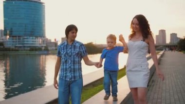 Şehir göletinin yanında yürüyen mutlu bir aile. Birlikte eğlenin.