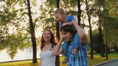 Mutlu ebeveynler kucağında sevimli bir çocuk, sarılıyor ve eğleniyorlar. 