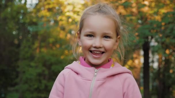 Πορτρέτο του όμορφου μικρού κοριτσιού κοιτάζοντας κάμερα και χαμογελώντας στο πάρκο του καλοκαιριού — Αρχείο Βίντεο