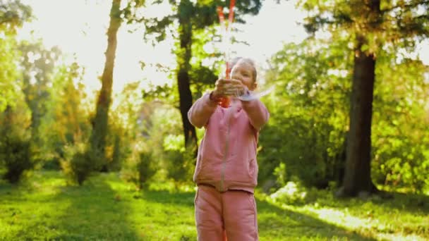 Lycklig liten flicka blåser såpbubblor, leka i parken utomhus med leksak pistol — Stockvideo