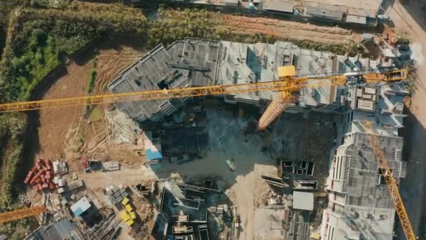 Pluma vista aérea de grúa torre grande eleva materiales de construcción en obra — Vídeo de stock