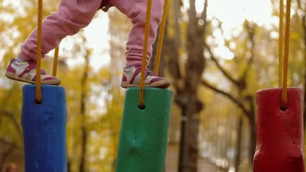 Pequeño niño hacer pasos y el equilibrio en el muñón de madera oscilante en el parque de la cuerda — Vídeo de stock