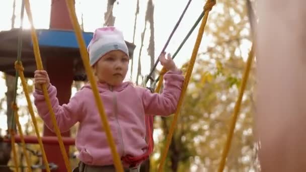 Ritratto di bambino che cammina e si equilibra sulla corda oscillante nel parco delle corde — Video Stock