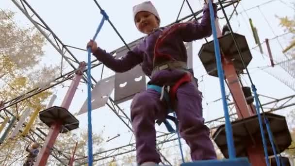 Bambina cercando di fare un passo, ma inciampa e scivola via nel parco corda — Video Stock